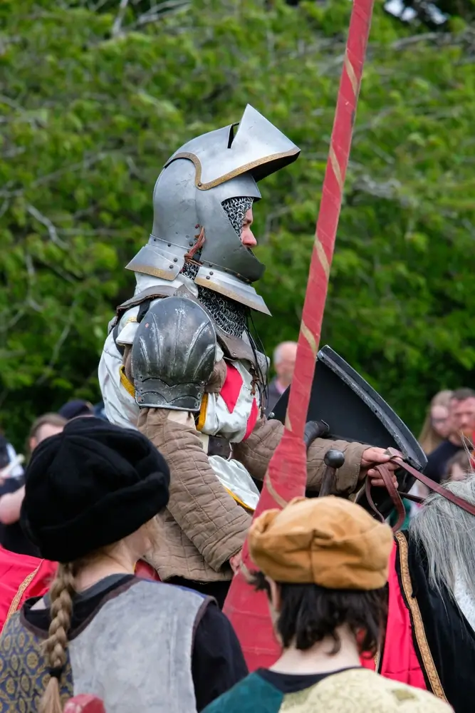 Caballero medieval portando un estandarte histórico rojo, representando al alférez que guiaba las huestes del rey.