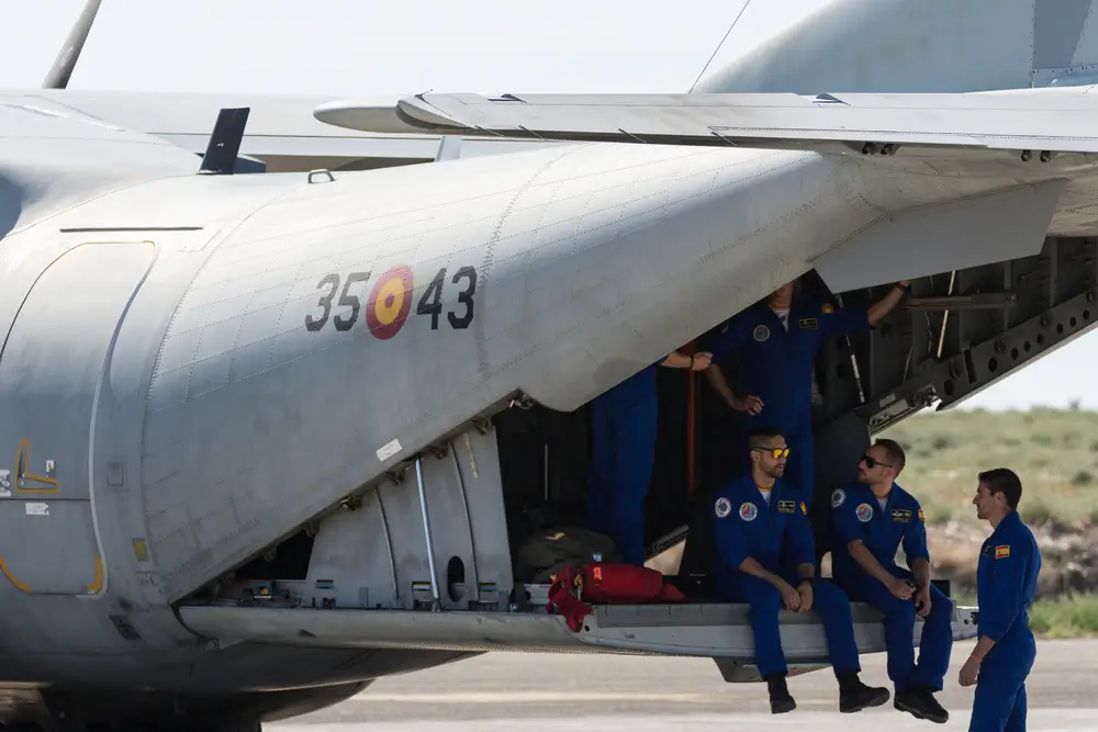 Soldados del Ejército del Aire español descansando en la rampa de un avión de transporte militar en una base aérea.