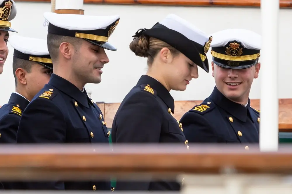 Oficiales de la Armada española con uniformes de gala y divisas doradas en las hombreras y gorras de plato.