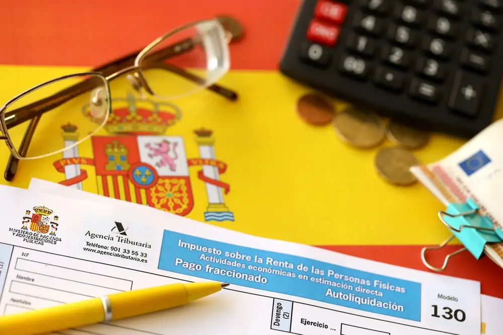 Formulaire fiscal espagnol, calculatrice et lunettes illustrant le calcul de la rémunération d'un militaire en Espagne.