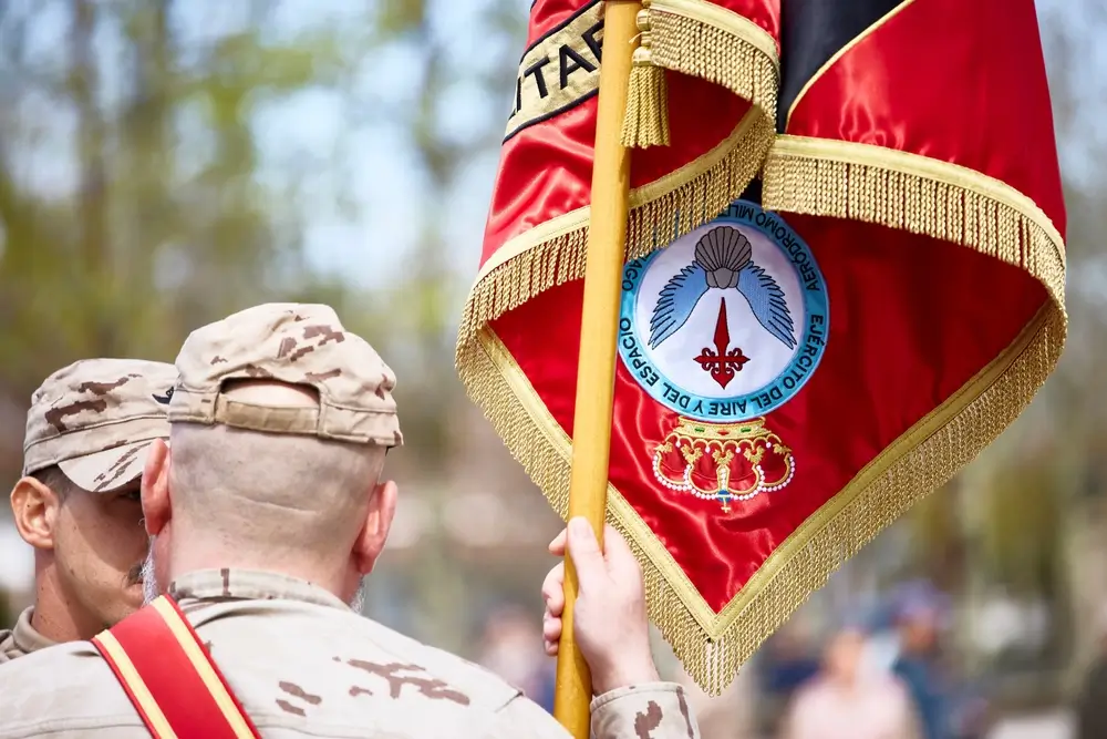 Oficial militar portando un estandarte durante una ceremonia, representando el papel del alférez en el ejército.