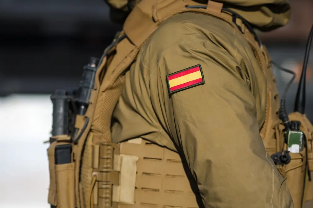 Militar español con equipamiento de campo y el parche de la bandera de España en la manga de su uniforme táctico.