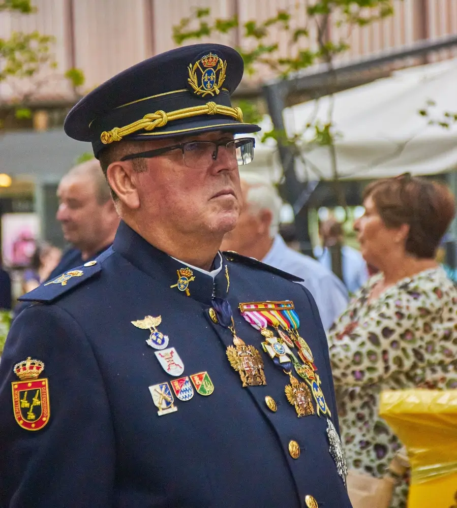 Oficial con uniforme militar de gala luciendo insignias de rango, como la estrella de seis puntas, y condecoraciones.