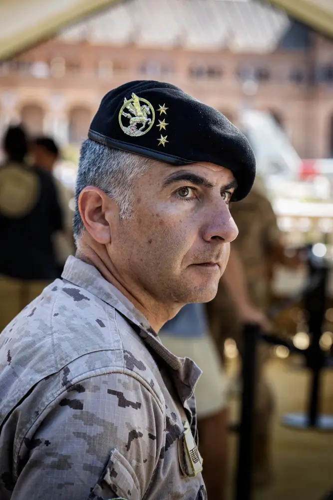 Militar veterano con uniforme de camuflaje y boina negra con tres estrellas, mirando de perfil con expresión seria.