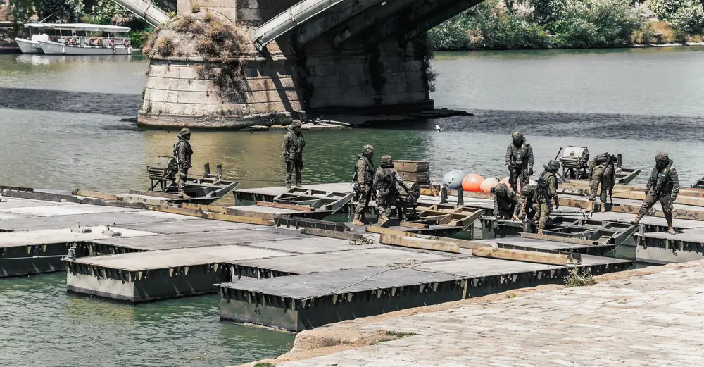 Soldados en un centro de formación militar practicando el montaje de puentes de pontones en el agua.