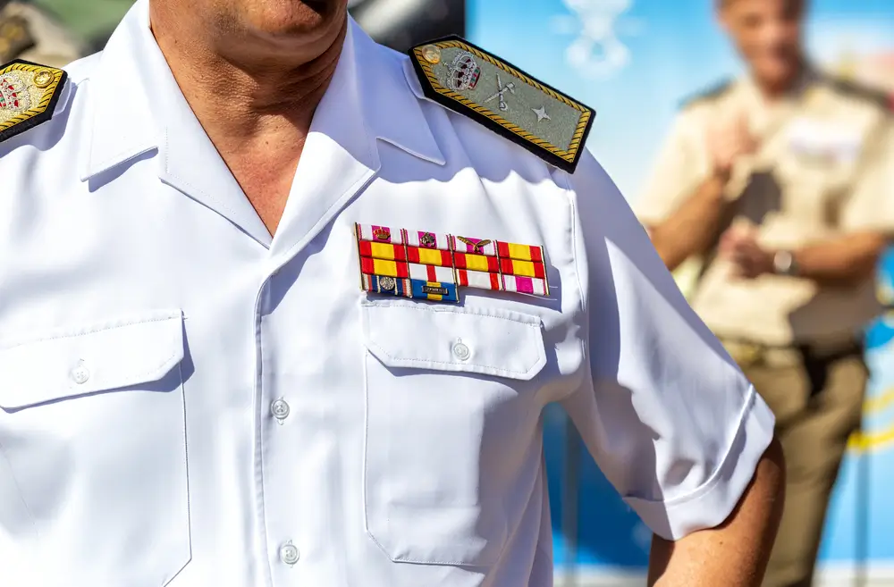 Detalle de las insignias de grados militares y condecoraciones en el uniforme blanco de un oficial español.