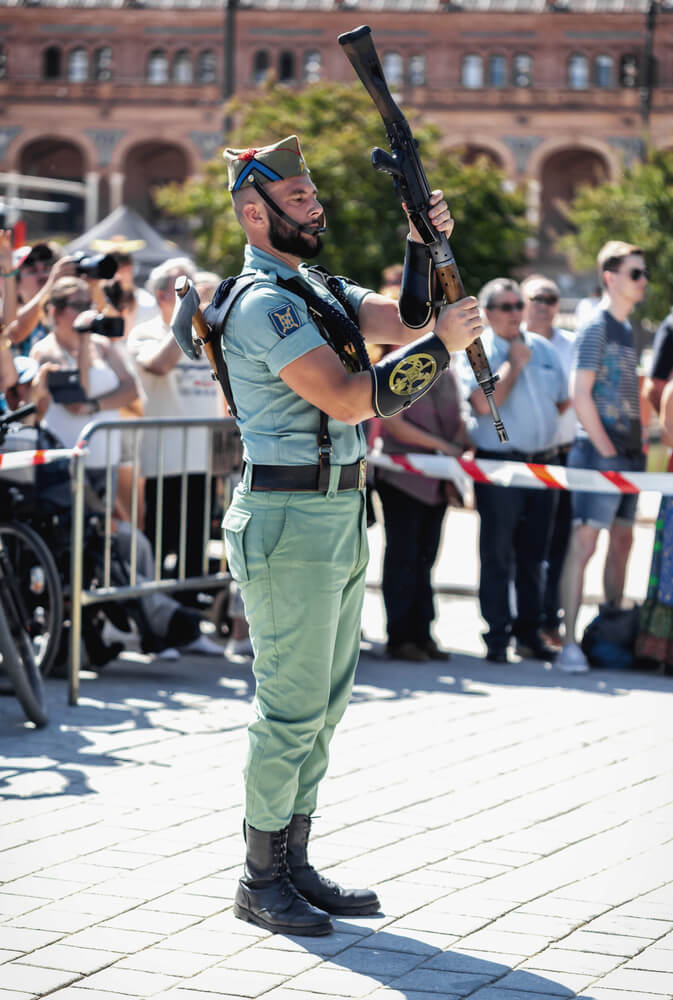 Militar de la Legión española con uniforme tradicional manejando su fusil en una jornada de formación al aire libre.