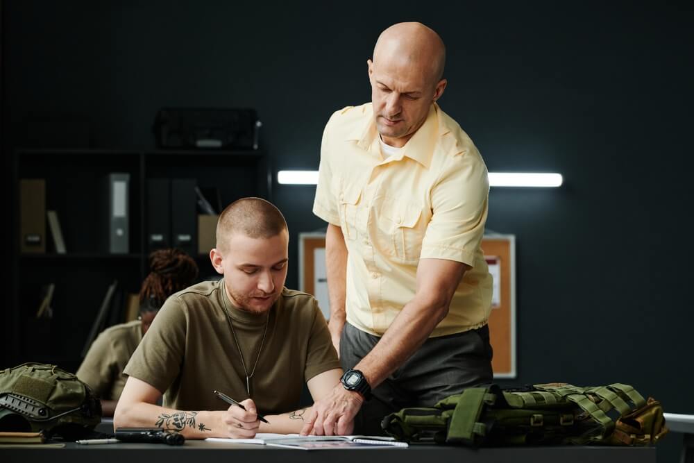 Instructor militar explicando el alfabeto fonético a soldados en formación dentro de un aula