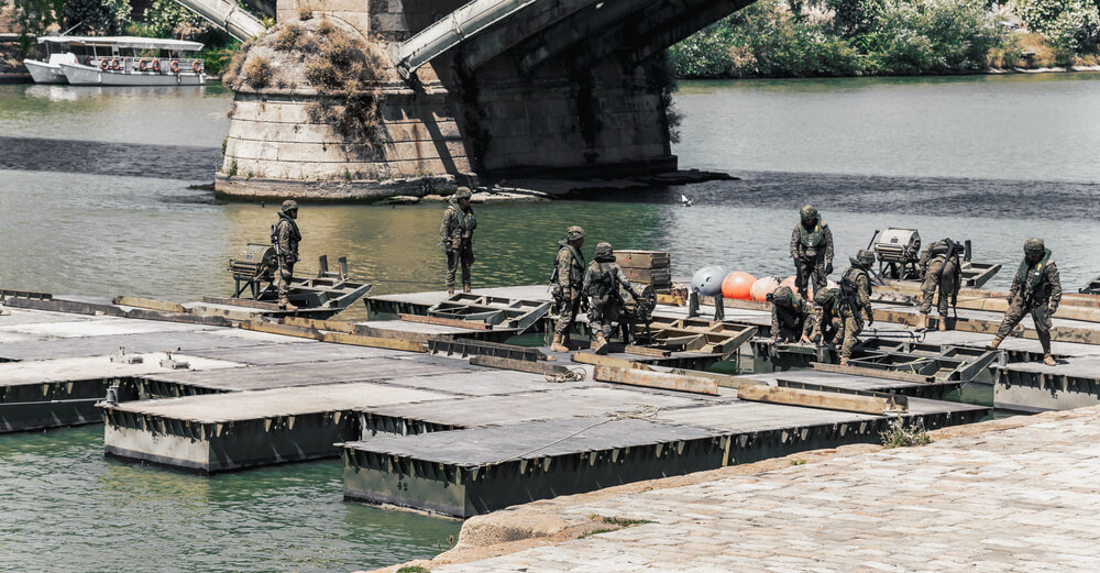 Soldados en un centro de formación militar practicando el montaje de puentes de pontones en el agua.