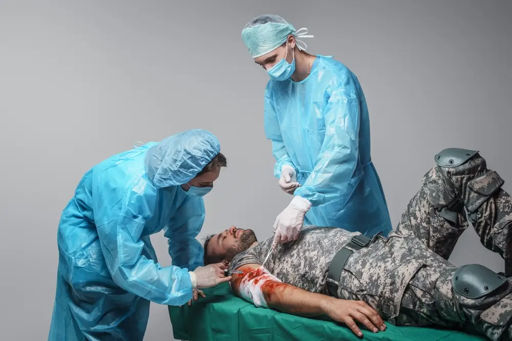 Sanitarios militares atendiendo la herida de un soldado durante un ejercicio de primeros auxilios en campaña.