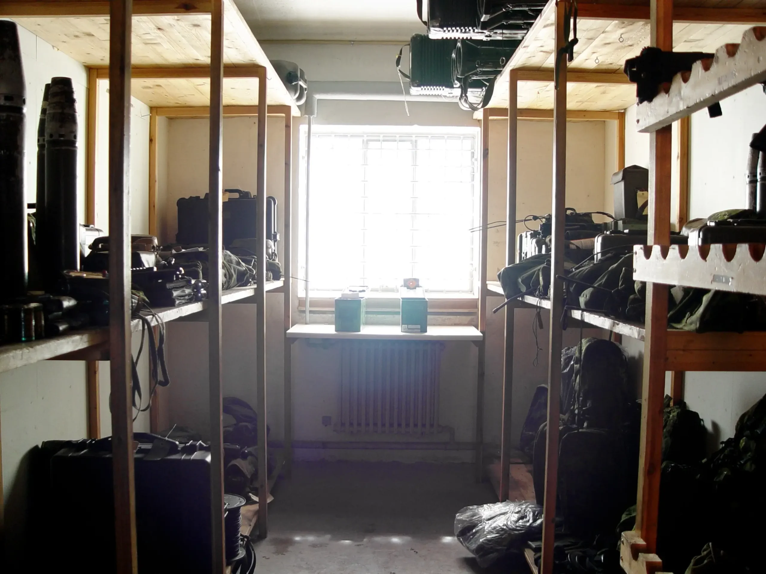Equipo y mochilas de soldados de tropa almacenados en estanterías de madera en el interior de una base militar.