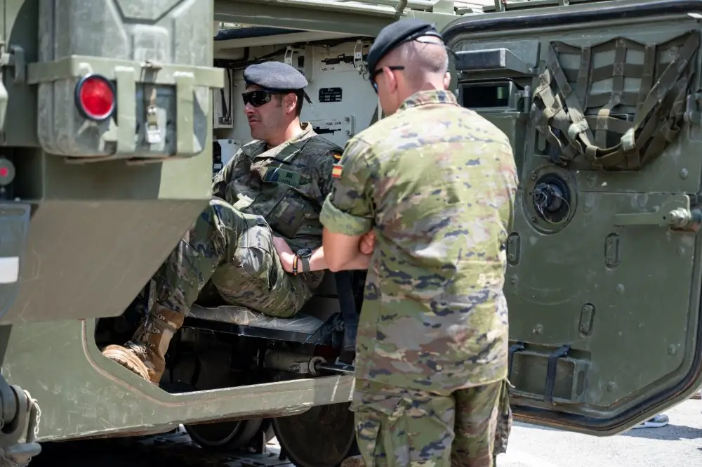 Militares españoles en un ejercicio de entrenamiento de campo y maniobras tácticas junto a un vehículo blindado.