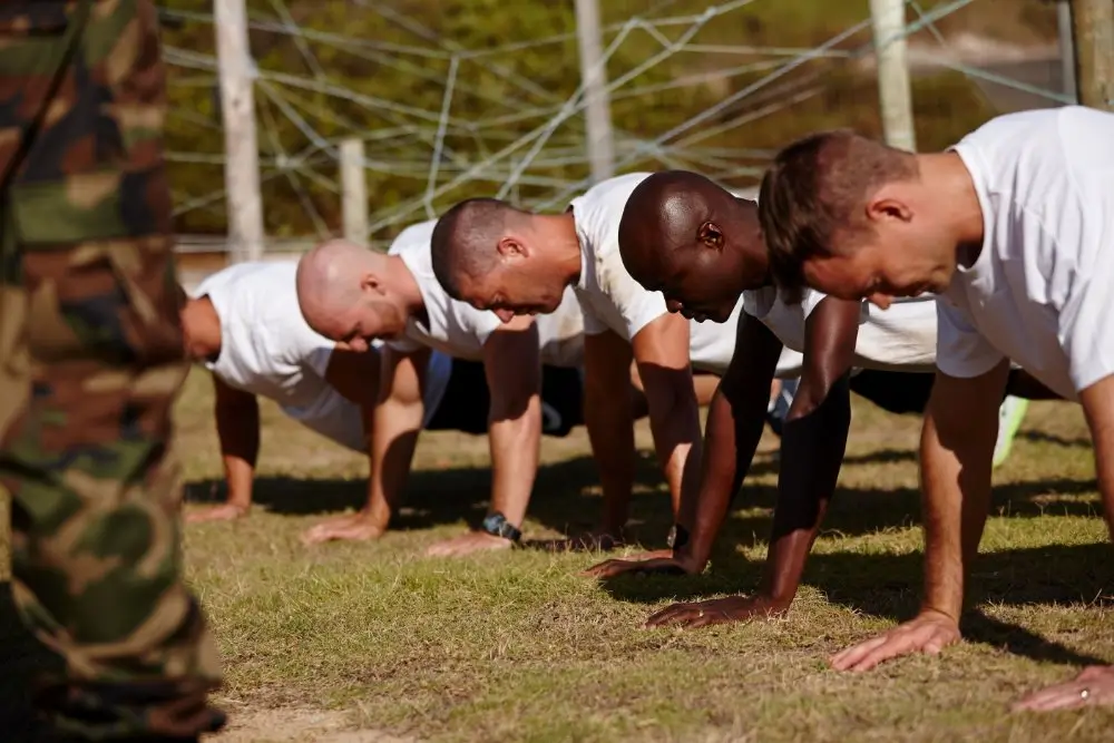 Aspirantes militares realizan flexiones en el césped durante una prueba de aptitud física para el acceso a suboficiales.