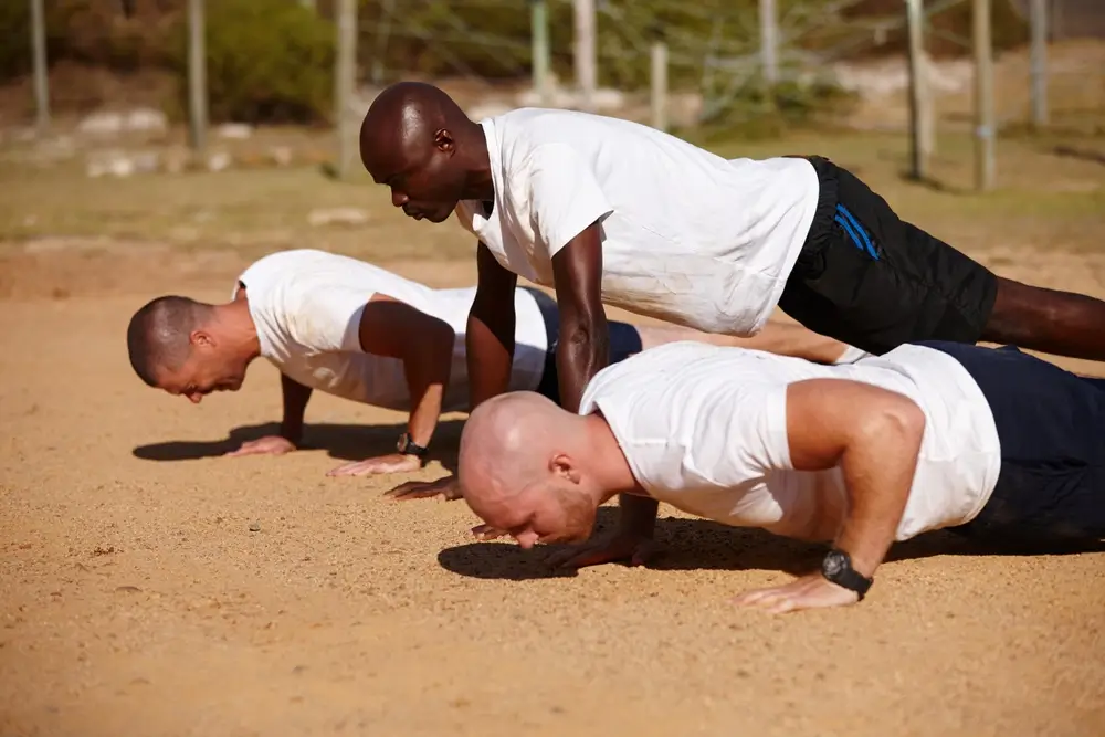 Reclutas realizan flexiones durante su instrucción física en un campo de entrenamiento militar.