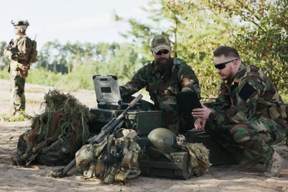 Soldados y reclutas militares en ejercicio exterior y formación técnica con equipos tácticos y dispositivos de campaña.