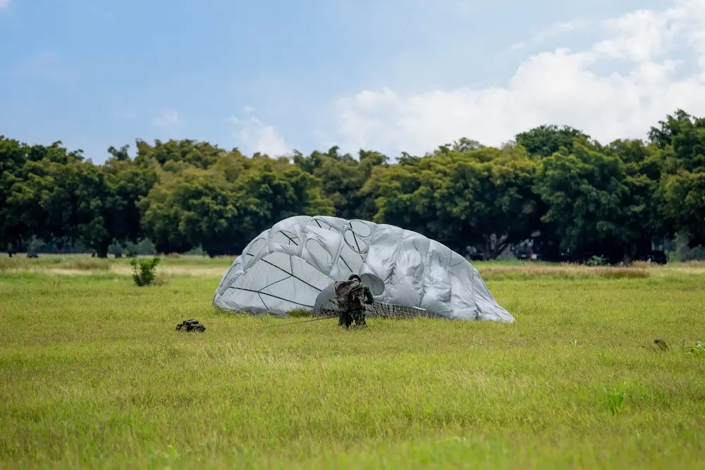 Paracaidista recogiendo su equipo en el campo de una base militar tras un salto de la Brigada Paracaidista.