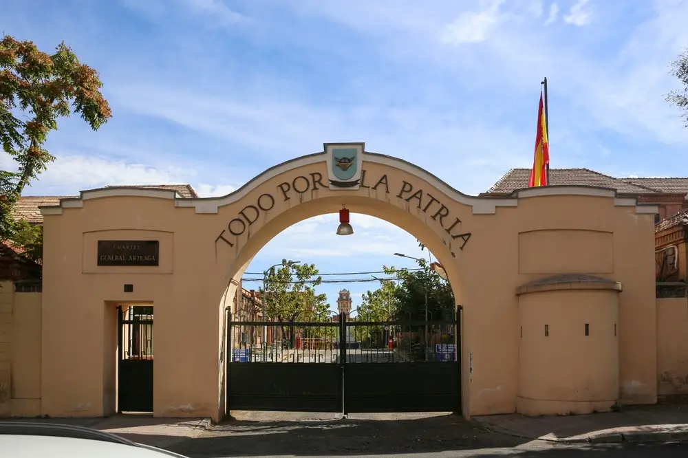 Entrada al Cuartel General Arteaga con el lema Todo por la Patria, bandera de España e instalaciones de formación militar.