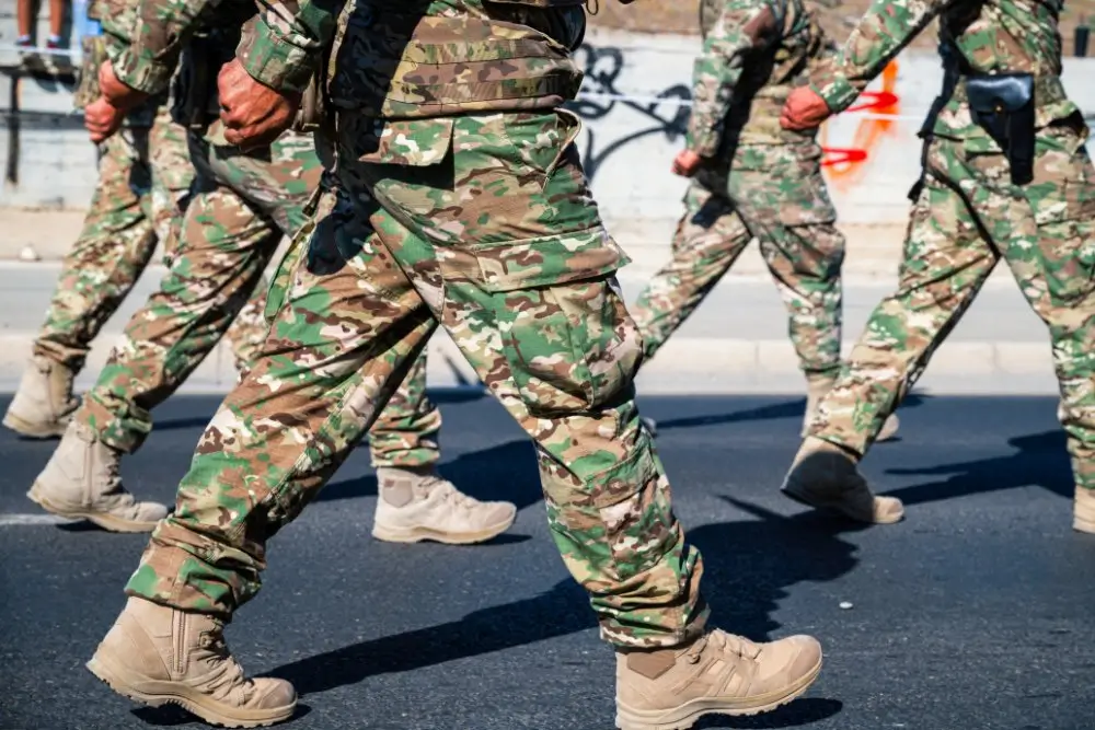 Soldados del Ejército de Tierra en formación militar marchando en un desfile oficial con uniformes de camuflaje.