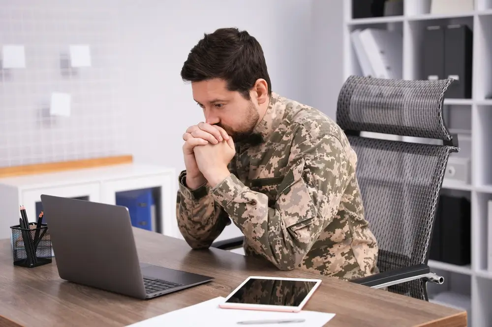 Militar en uniforme estudiando con libros abiertos en un escritorio