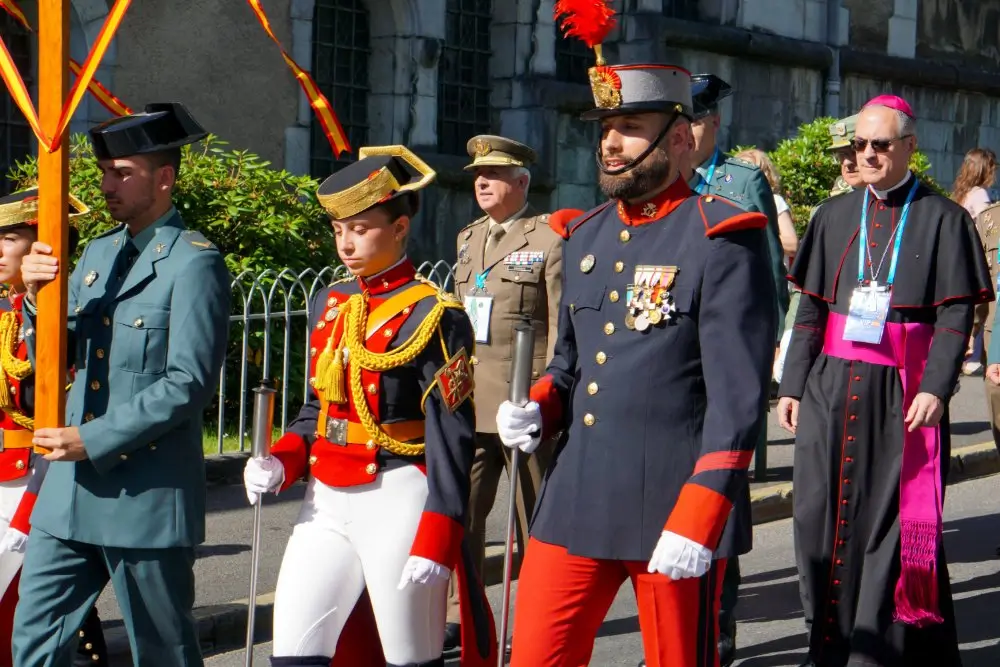 Militares con uniformes de gala, insignias y divisas de rango en un desfile oficial con emblemas del ejército.