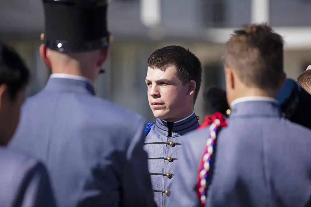 Cadete con uniforme de gala en formación en el patio de armas de una academia militar durante su periodo de instrucción.