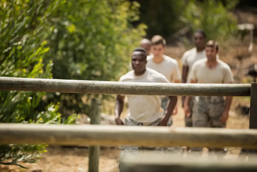 Soldados corriendo en formación durante una sesión de preparación física y entrenamiento militar al aire libre.