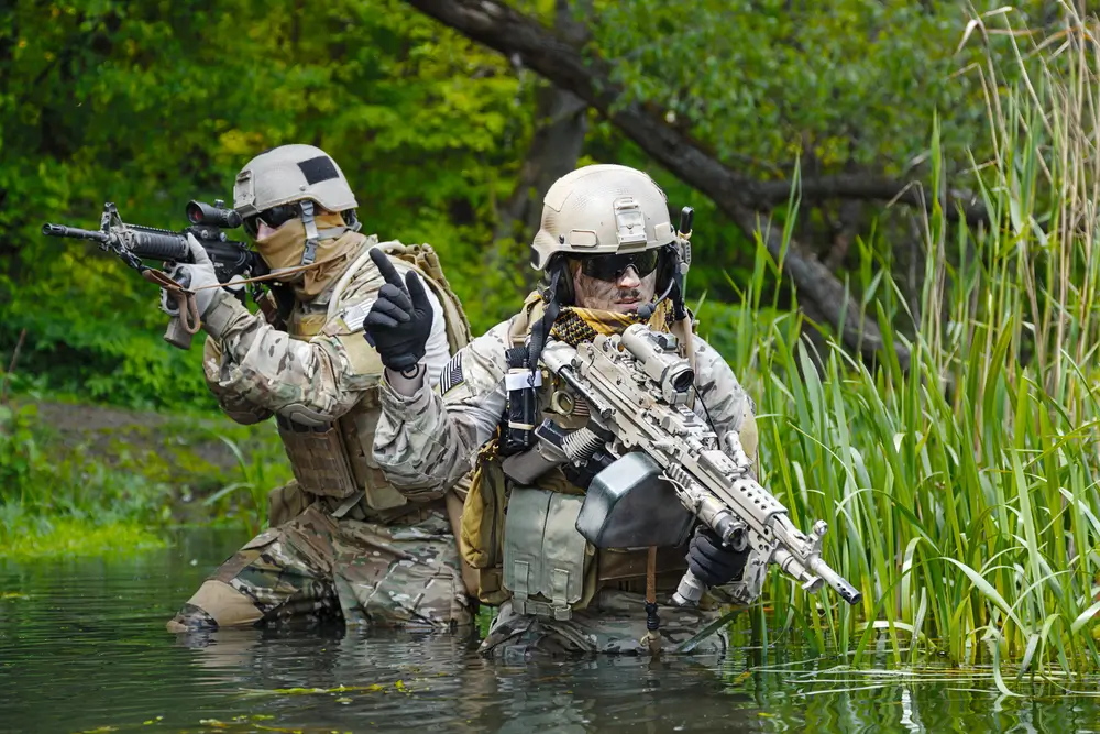 Soldados de operaciones especiales del MOE (boinas verdes) en una misión táctica cruzando un río con equipo de combate.