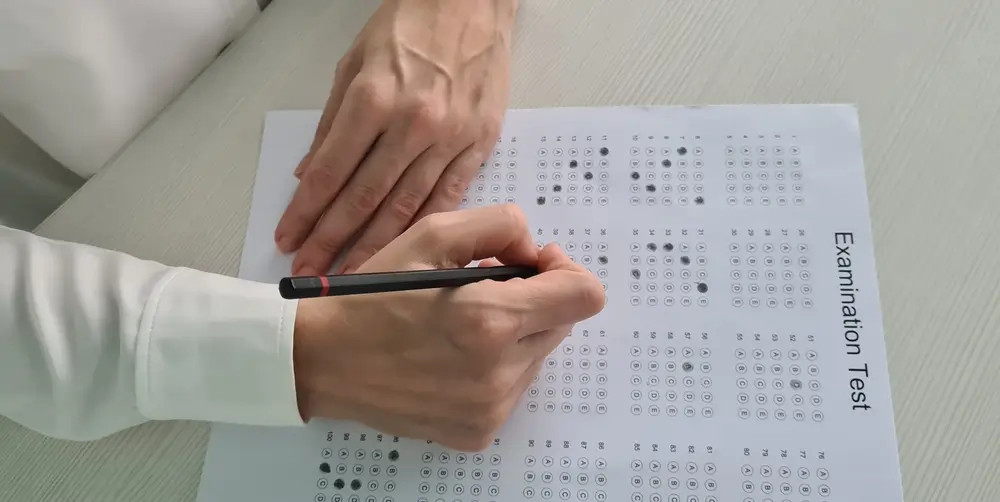 Candidato completando una hoja de examen tipo test durante las pruebas de reclutamiento en un centro de selección.